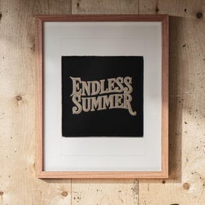 Endless Summer Patch print in a Red Oak frame with a white mat, hanging above the workbench in a surf garage.
