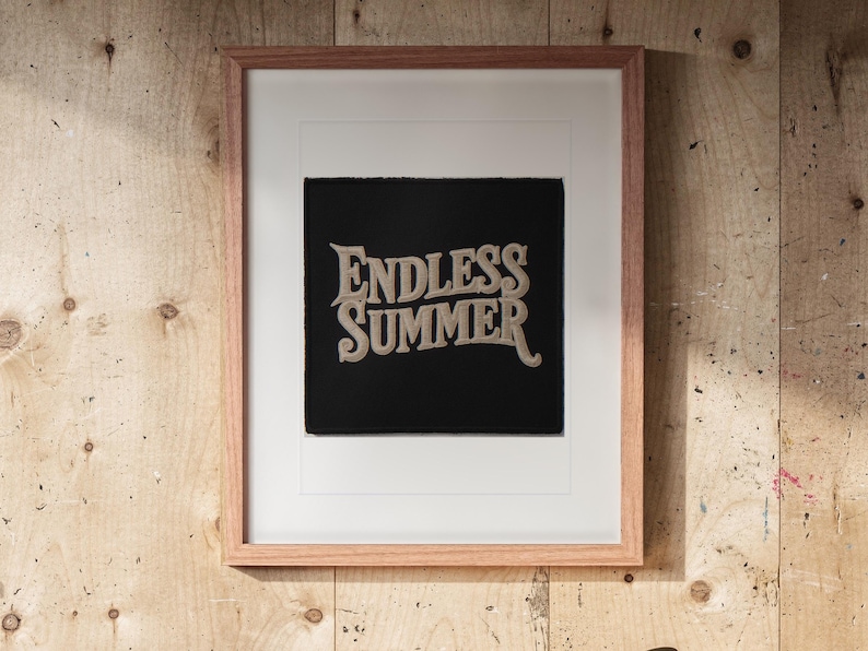 Endless Summer Patch print in a Red Oak frame with a white mat, hanging above the workbench in a surf garage.