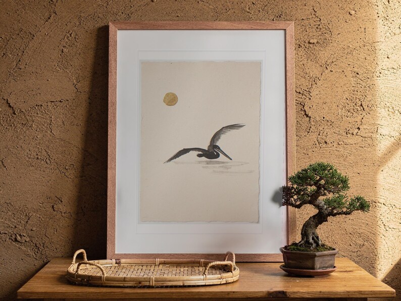 Flying Pelican Ink Style print in a Red Oak frame with a white mat, leaning against the wall above the tea table in a tea room.