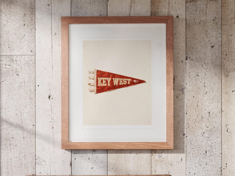 Key West Surf Pennant print in a Red Oak frame with a white mat, hanging above the trunk in a beach house loft.