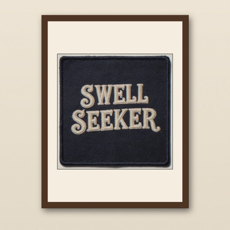 Swell Seeker Embroidered Patch Print - walnut framed art print with cream mat on plaster wall