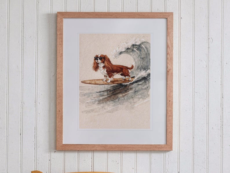 Cavalier King Charles Spaniel Surfing print in a Red Oak frame with a white mat, hanging above the bookshelf in a kids' room.