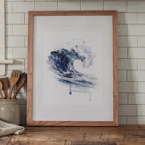 Prussian Blue Wave Watercolor print in a Red Oak frame with a white mat, leaning on the counter against the backsplash in a cottage kitchen.