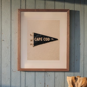 Cape Cod Surf Pennant print in a Red Oak frame with a white mat, hanging above the bench in a beach cottage entryway.