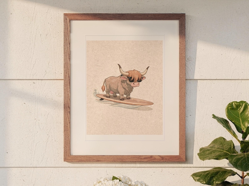 Highland Cow Surfing print in a Red Oak frame with a white mat, hanging above the table in a sunroom.