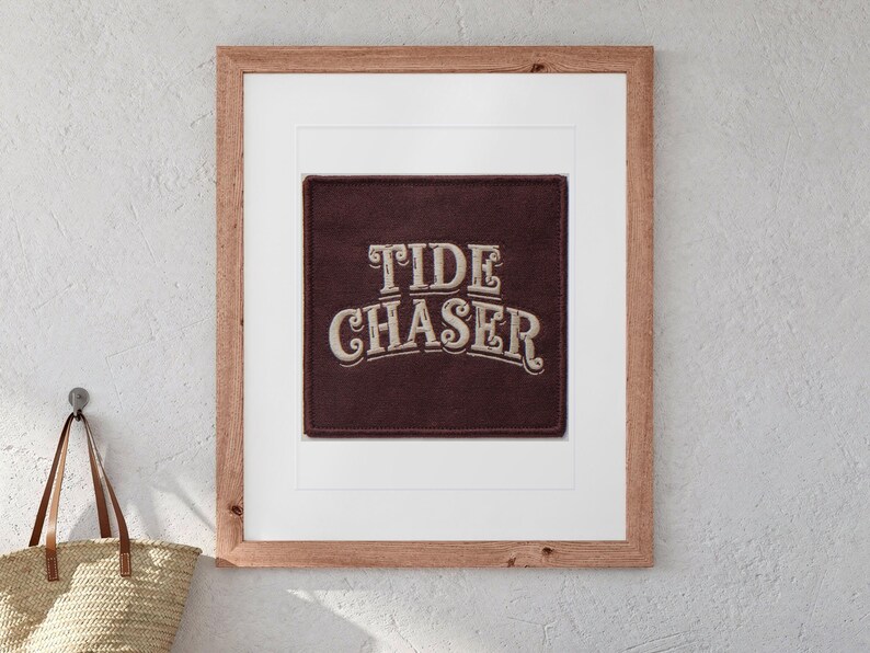 Tide Chaser Patch print in a Red Oak frame with a white mat, hanging above the bench in a beach cottage entryway.