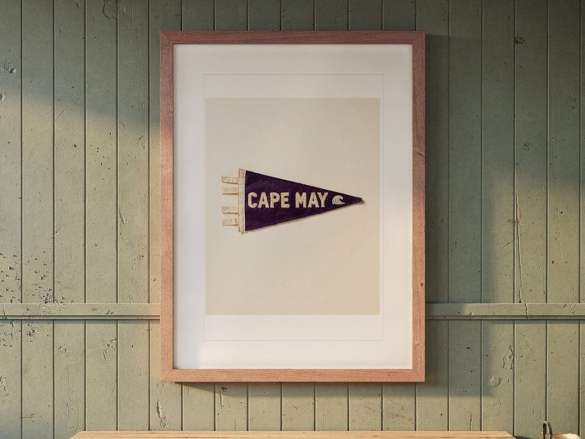 Cape May Surf Pennant print in a Red Oak frame with a white mat, hanging above the bench in a mudroom.
