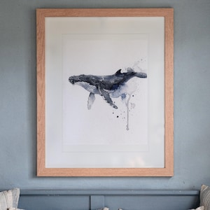 Humpback Whale print in a Red Oak frame with a white mat, hanging above the bench in a breakfast nook.