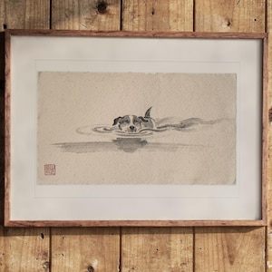 Puede incluir: Una pintura a tinta sobre papel texturizado enmarcada que representa a un perro nadando en el agua, creando suaves ondas. La obra presenta un pequeño sello rojo en la esquina inferior izquierda y está en un marco de madera.