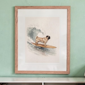Pug Surfing printable art, shown printed in a Red Oak frame with a white mat, hanging above the bookshelf in a kids' room.