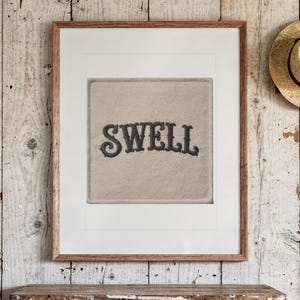 Swell Patch print in a Red Oak frame with a white mat, hanging above the dresser in a surf shack bedroom.