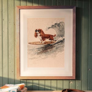 Cavalier King Charles Spaniel Surfing printable art, shown printed in a Red Oak frame with a white mat, hanging above the bench in a mudroom.