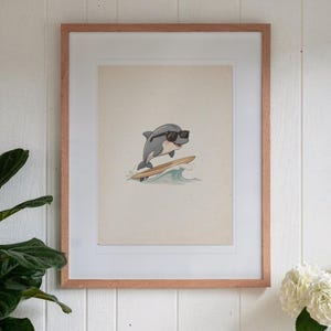 Dolphin Surfing print in a Red Oak frame with a white mat, hanging above the console in a sunroom.