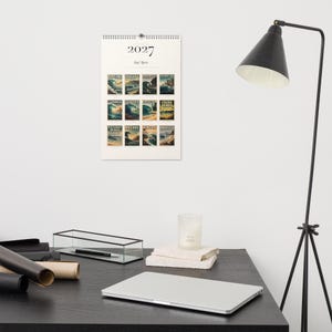 2027 Surf Spots wall calendar hanging above a desk.