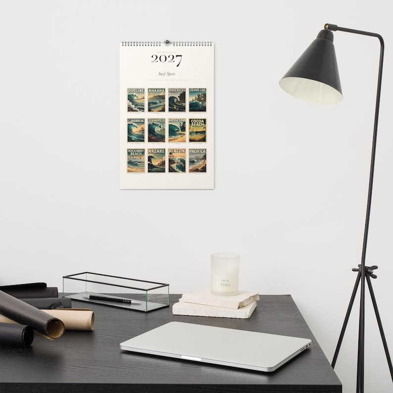 2027 Surf Spots wall calendar hanging above a desk.