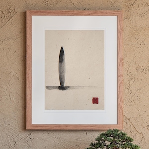 May include: A framed wall art piece featuring a vertical black ink brush stroke resembling a surfboard shape on textured beige paper. A horizontal black ink line sits at the base, and a small solid red square is positioned in the lower right corner.