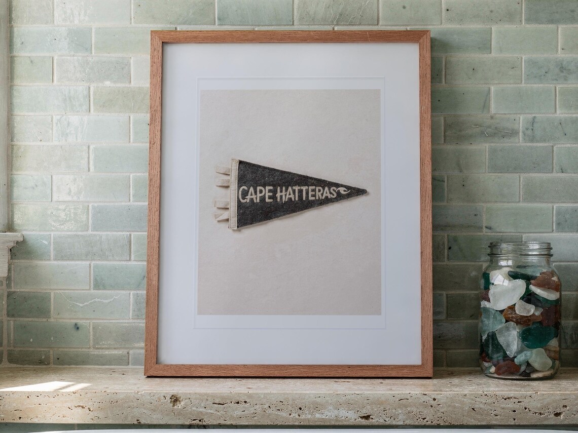 Cape Hatteras print in a Red Oak frame with a white mat, leaning on the ledge against the wall in a bright bathroom.