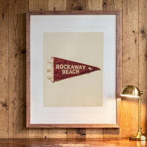 Rockaway Beach Surf Pennant print in a Red Oak frame with a white mat, hanging above the desk in a home office.