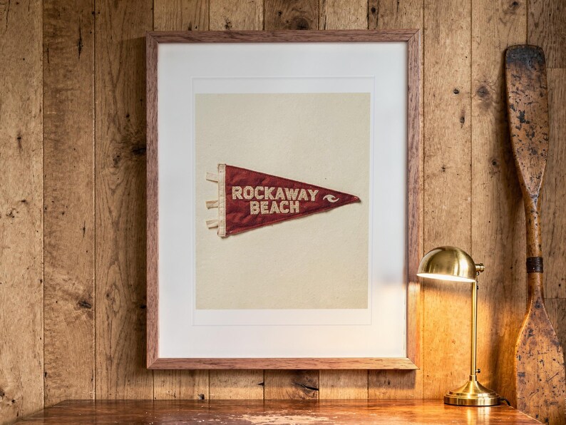 Rockaway Beach Surf Pennant print in a Red Oak frame with a white mat, hanging above the desk in a home office.