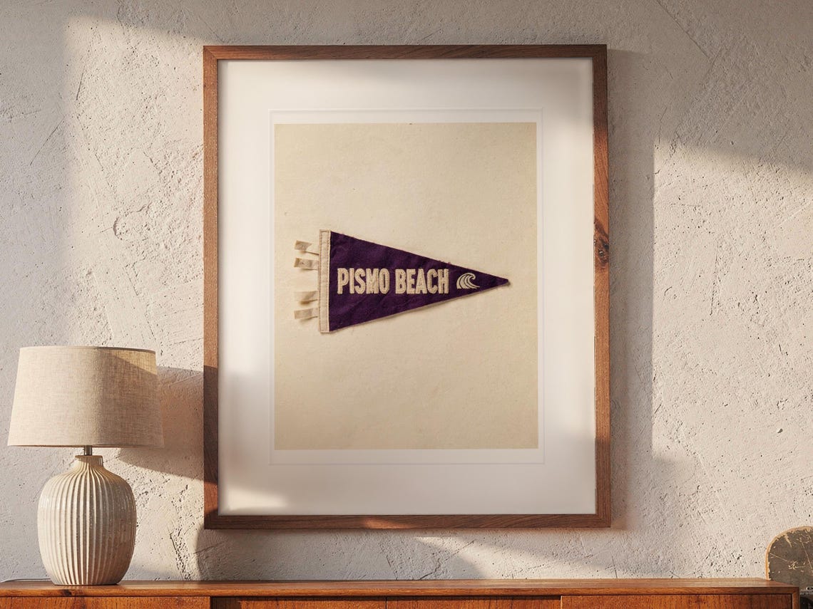 Pismo Beach print in a Red Oak frame with a white mat, hanging above the credenza in a mid-century living room.
