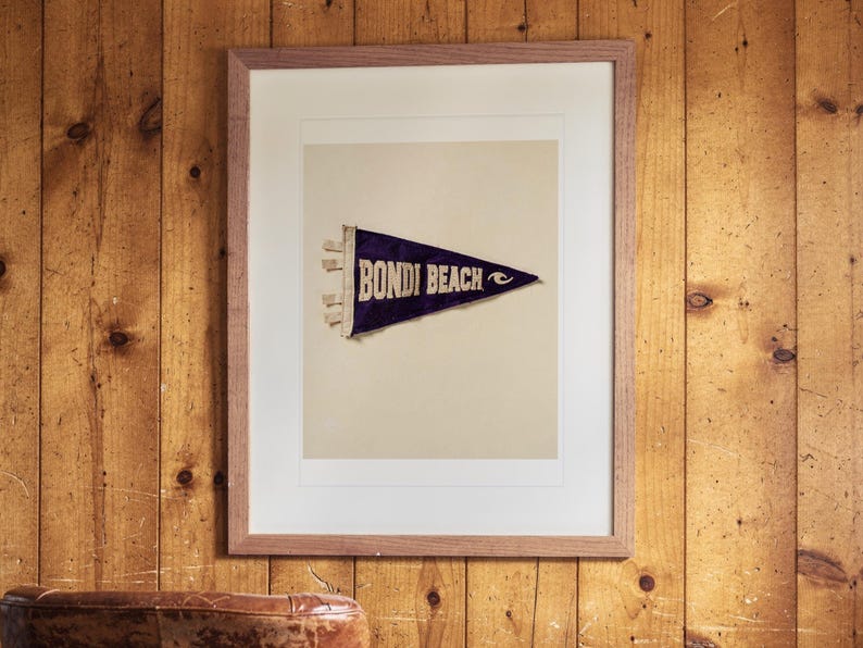 Bondi Beach print in a Red Oak frame with a white mat, hanging on the paneling in a 1960s den.
