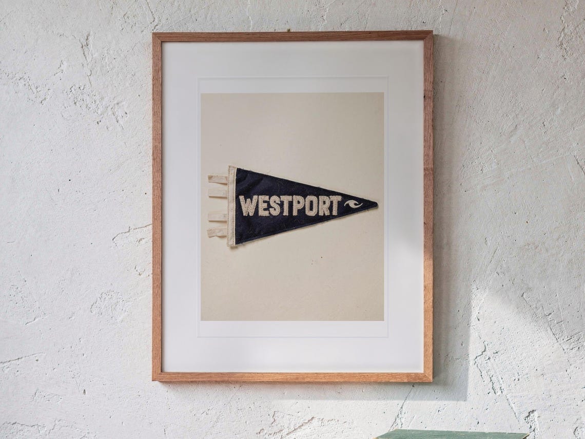 Westport Surf Pennant print in a Red Oak frame with a white mat, hanging above the sideboard in a mid-century living room.