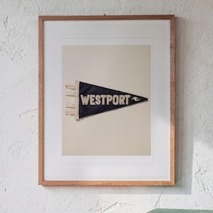Westport Surf Pennant print in a Red Oak frame with a white mat, hanging above the sideboard in a mid-century living room.