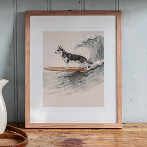 Husky Surfing print in a Red Oak frame with a white mat, leaning on the counter against the backsplash in a cottage kitchen.