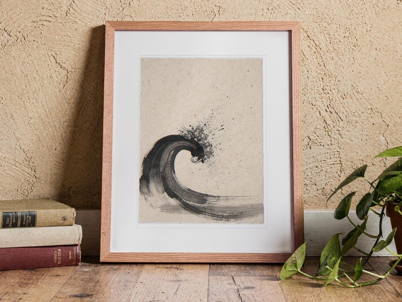 Curling Wave Ink Style print in a Red Oak frame with a white mat, standing on the floor, leaning back slightly against the wall in a living room floor lean.