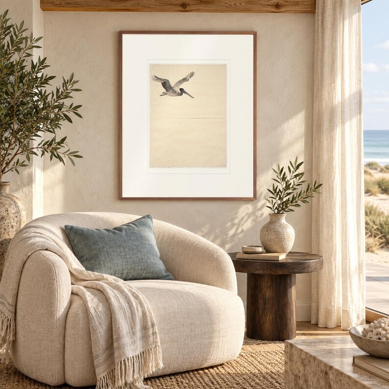 Flying Pelican Ink Style print in a Red Oak frame with a white mat in a light-filled coastal sitting room.
