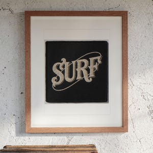 Surf Patch print in a Red Oak frame with a white mat, hanging above the trunk in a beach house loft.