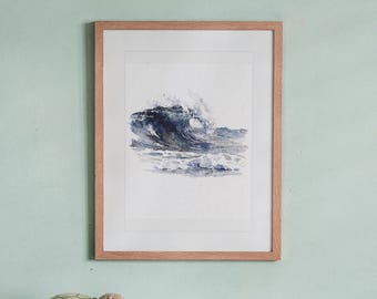 May include: A framed watercolor painting of a crashing ocean wave in shades of deep blue and grey. The artwork is set within a light-toned wooden frame with a white mat border, displaying a dynamic sea scene with white foam and spray.