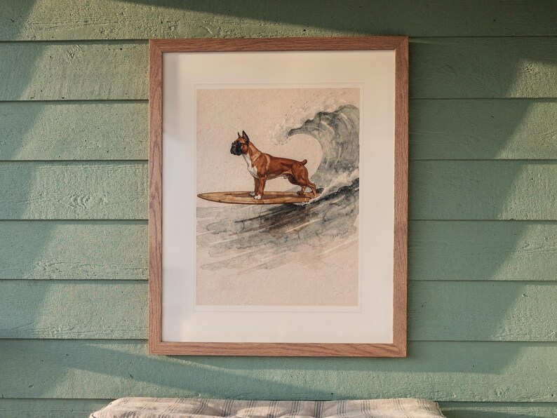 Boxer Surfing printable art, shown printed in a Red Oak frame with a white mat, hanging above the bench in a screened beach porch.