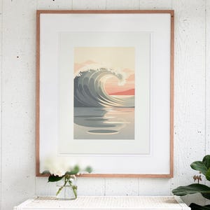 May include: A framed art print featuring a stylized illustration of a large ocean wave curling against a soft sunset sky. The color palette includes muted tones of gray, cream, and peach, with the wave reflecting on the calm water surface.
