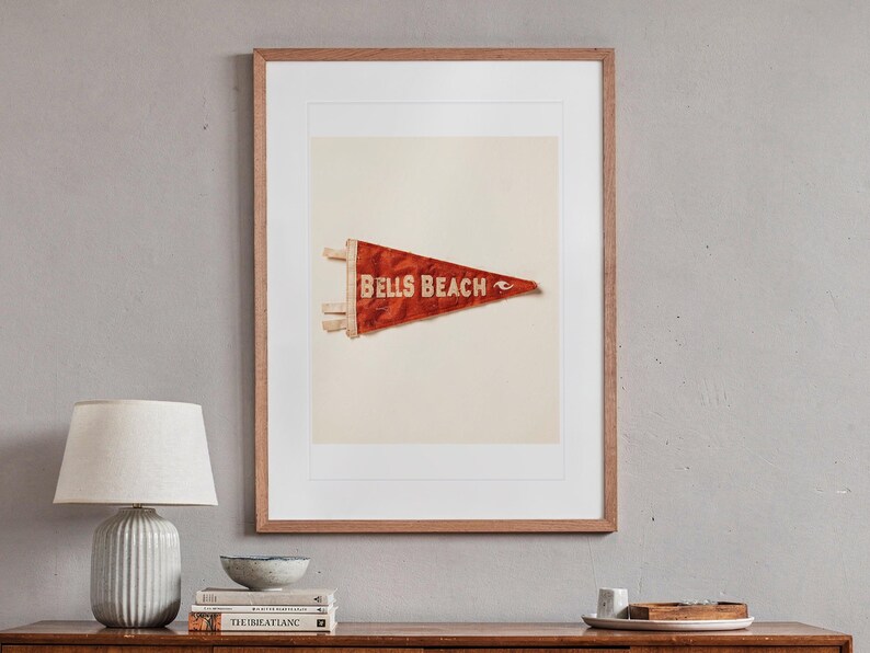 Bells Beach Surf Pennant print in a Red Oak frame with a white mat, hanging above the sideboard in a mid-century living room.