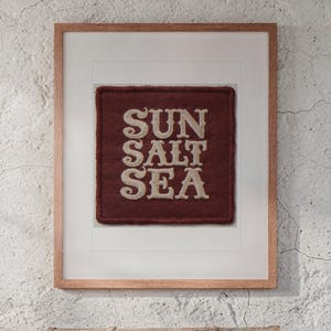 Sun Salt Sea Patch print in a Red Oak frame with a white mat, hanging above the trunk in a beach house loft.