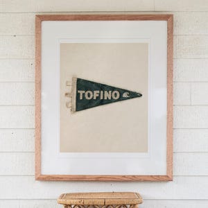 Tofino Surf Pennant print in a Red Oak frame with a white mat, hanging above the table in a screened beach porch.