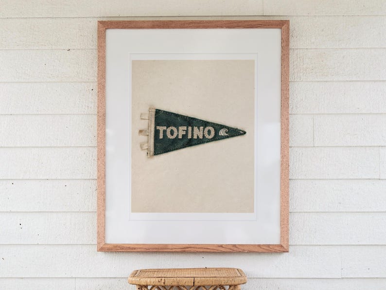 Tofino Surf Pennant print in a Red Oak frame with a white mat, hanging above the table in a screened beach porch.