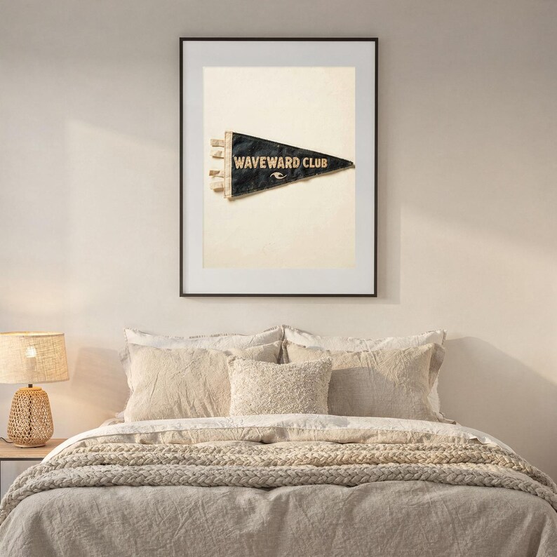 Waveward Club printable surf pennant styled above a bed in a calm coastal bedroom
