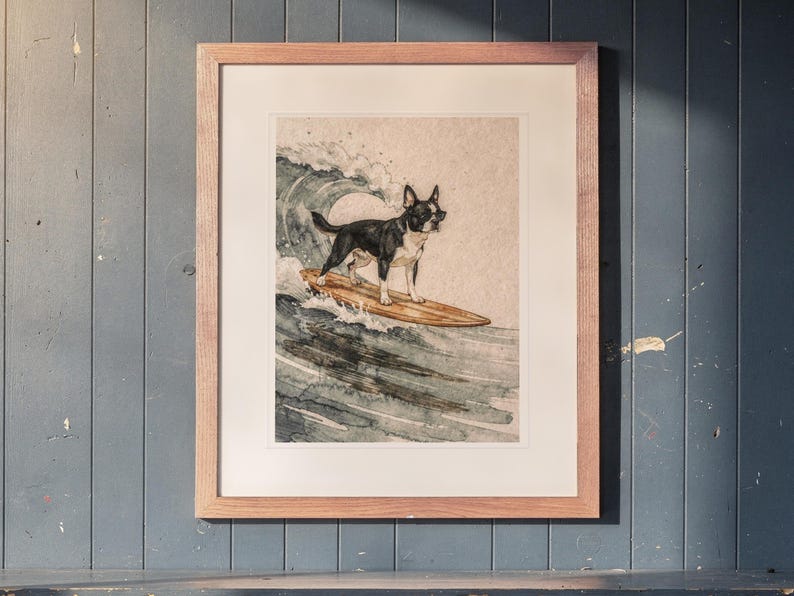 Boston Terrier Surfing printable art, shown printed in a Red Oak frame with a white mat, hanging above the cubbies in a mudroom.