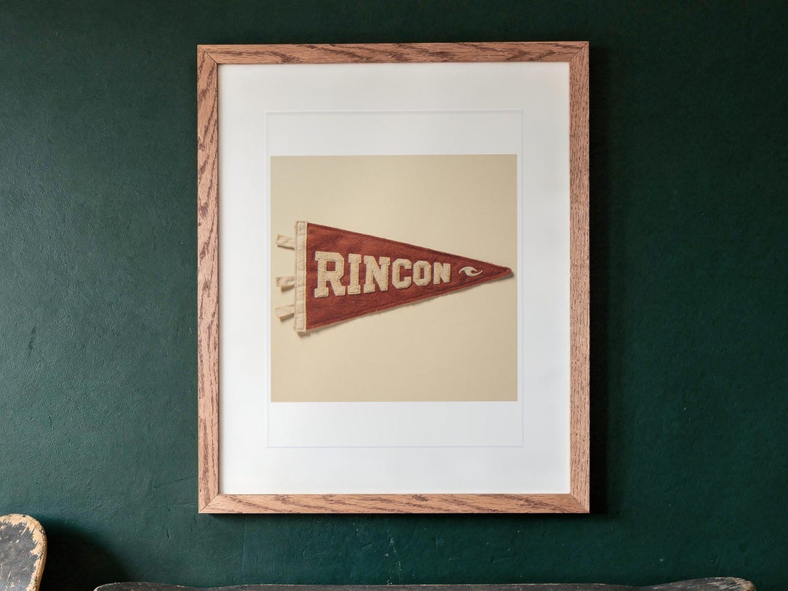 Rincon Surf Pennant print in a Red Oak frame with a white mat, hanging above the cabinet in a game room.