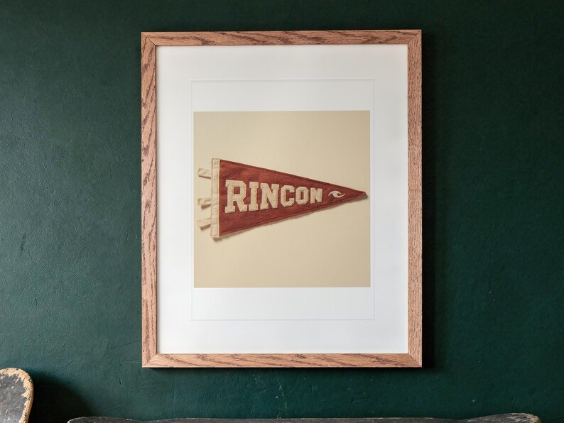 Rincon Surf Pennant print in a Red Oak frame with a white mat, hanging above the cabinet in a game room.
