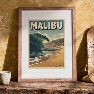 Malibu Surf Travel Poster print in a Red Oak frame with a white mat, leaning on the bench against the wall in a boho living room.