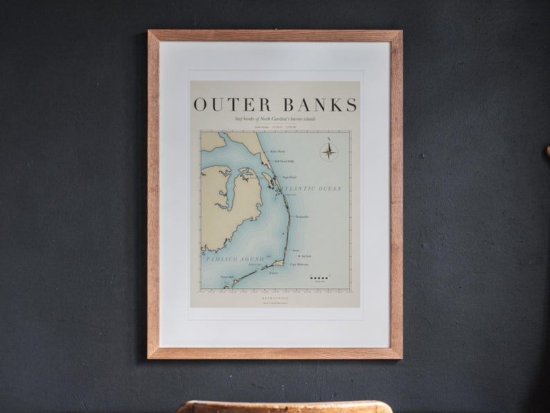 Outer Banks Surf Map printable art, shown printed in a Red Oak frame with a white mat, hanging above the desk in a home office.