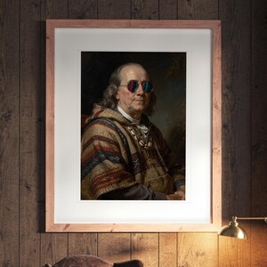 May include: A framed portrait of Benjamin Franklin wearing colorful round sunglasses and a patterned brown, red, and blue poncho. The artwork is displayed in a light wood frame with a white mat, hanging on a dark wood paneled wall.