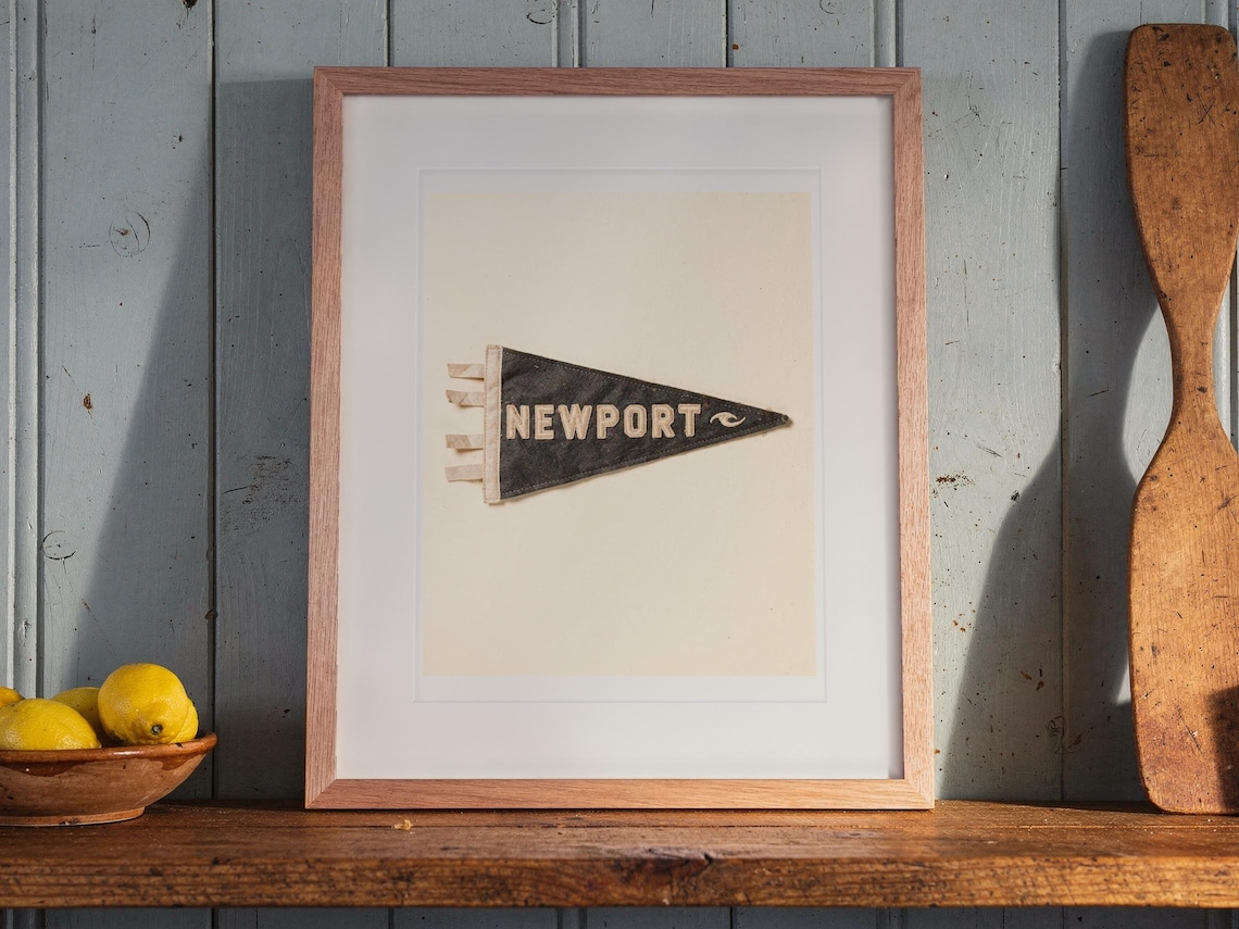 Newport print in a Red Oak frame with a white mat, leaning on the shelf against the wall in a cottage kitchen.