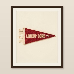 Lineup Lore vintage felt surf pennant printable displayed in a warm wood frame on a softly lit neutral wall