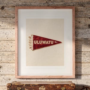 Uluwatu Surf Pennant print in a Red Oak frame with a white mat, hanging above the trunk in a beach house loft.