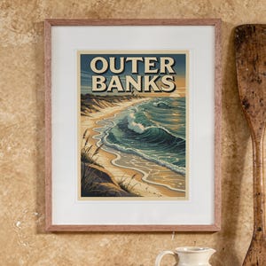 Outer Banks Surf Travel Poster print in a Red Oak frame with a white mat, hanging above the table in a boho living room.