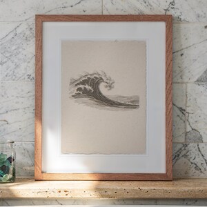 Vintage Wave Etching printable art, shown printed in a Red Oak frame with a white mat, leaning on the ledge against the wall in a bright bathroom.